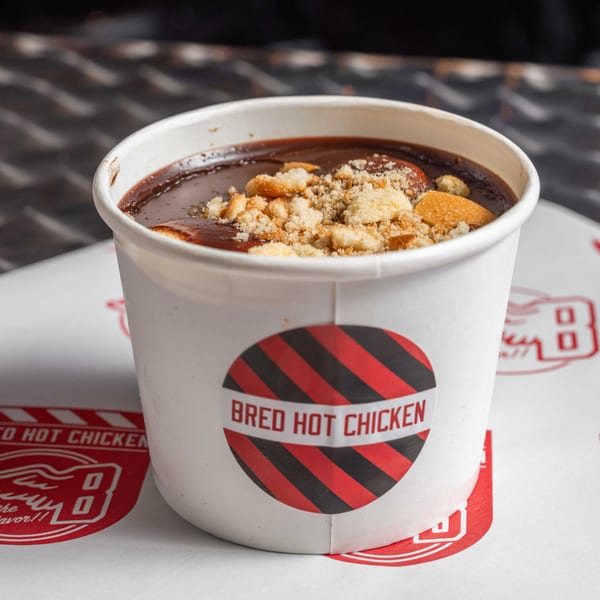 A Bred Hot Chicken branded cup filled with chocolate pudding and topped with cookie crumbles.
