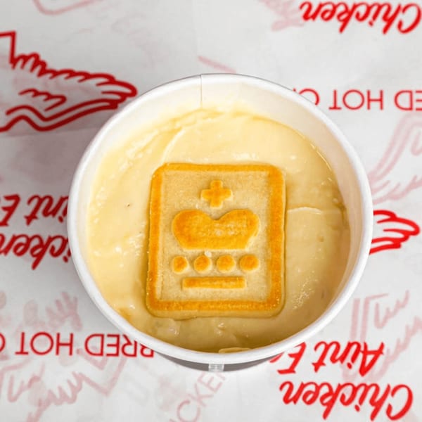 Bred Hot Chicken's banana pudding dessert with a vanilla wafer cookie on top, served in a white cup.