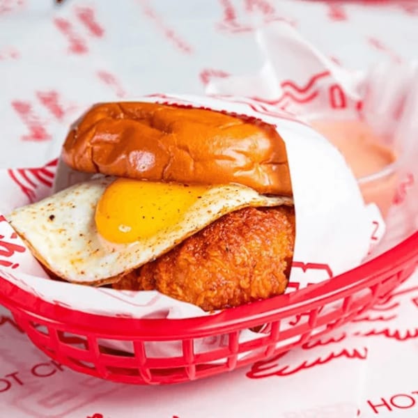 Bred Hot Chicken sandwich with fried chicken, fried egg, and bun in a red basket.